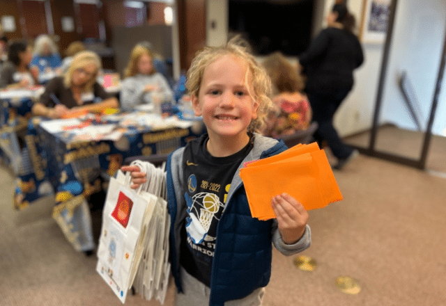 Young boy holds up decorated holiday gift bags.